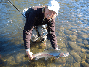 Woman holding fish in water on fishing line